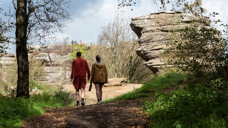 A couple walk along the accessible paths at Brimham rocks on an autumnal morning